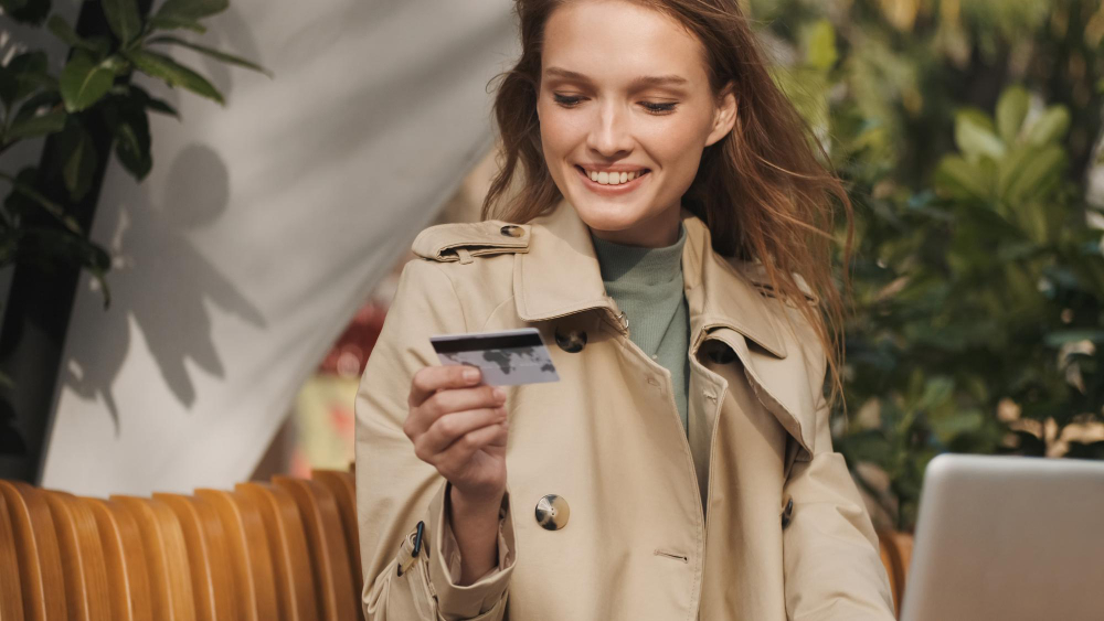 אישה יפה מחייכת מחזיקה כרטיס אשארי ברקע משרדי ירוק