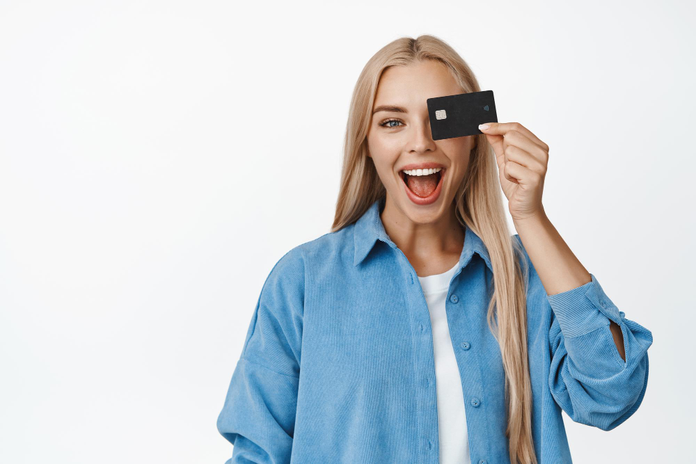 אישה בלונדינית מחייכת מחזיקה כרטיס אשראי ברקע לבן