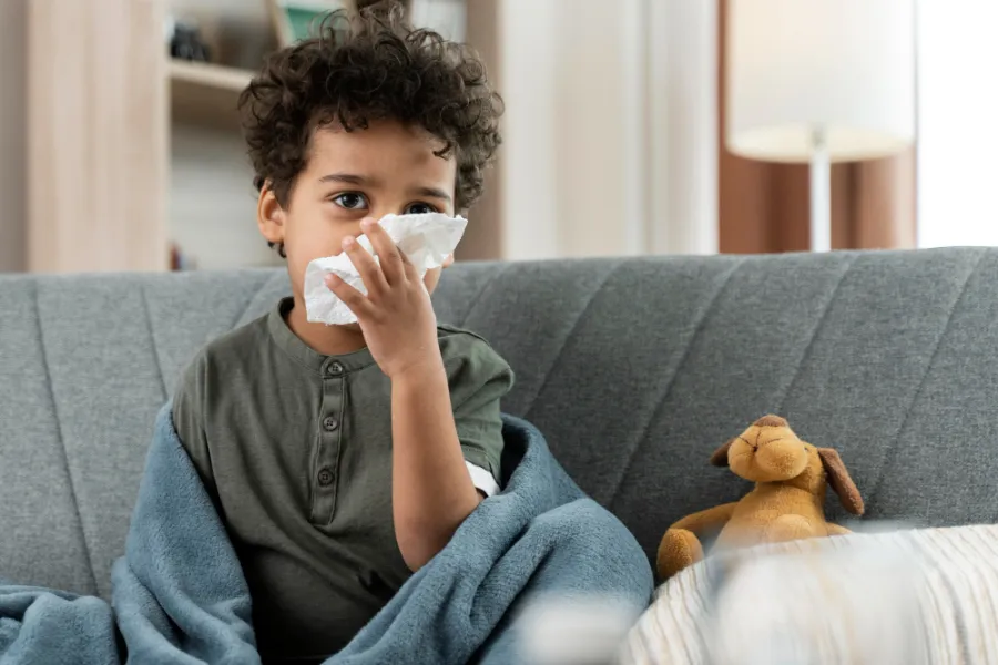 אלרגיה רפואית לבוטנים - ילד קטן בן 8 שמחזיק נייר טואלאט קונספט חולה בבית