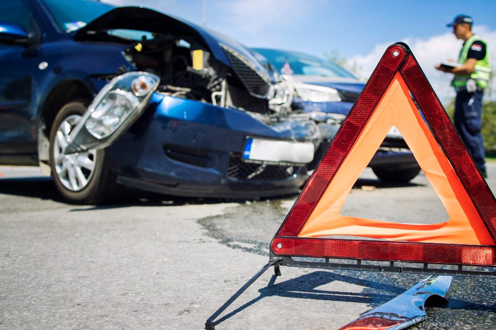 ביטוח רכב שמכסה רכב לאחר תאונה ומשולש אזהרה בכביש